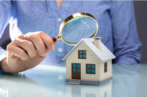 avaliador de imóveis com uma lupa sobre uma maquete de uma casa