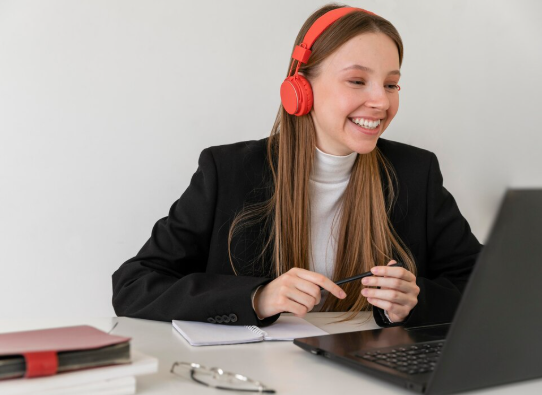 moça com fone de ouvido vermelho no computador, simulando estar estudando.